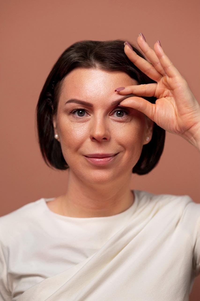 Mulher tocando a região dos olhos em imagem ilustrativa sobre rejuvenescimento do olhar.